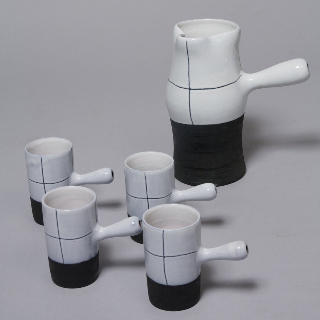 Five Piece Service by Jacques Innocenti: Five piece coffee or mocha service, a handled pitcher and four handled cups, each of white ceramic with black sgraffito markings and black lower half. By Jacques Innocenti, French 1950s. Signed to und