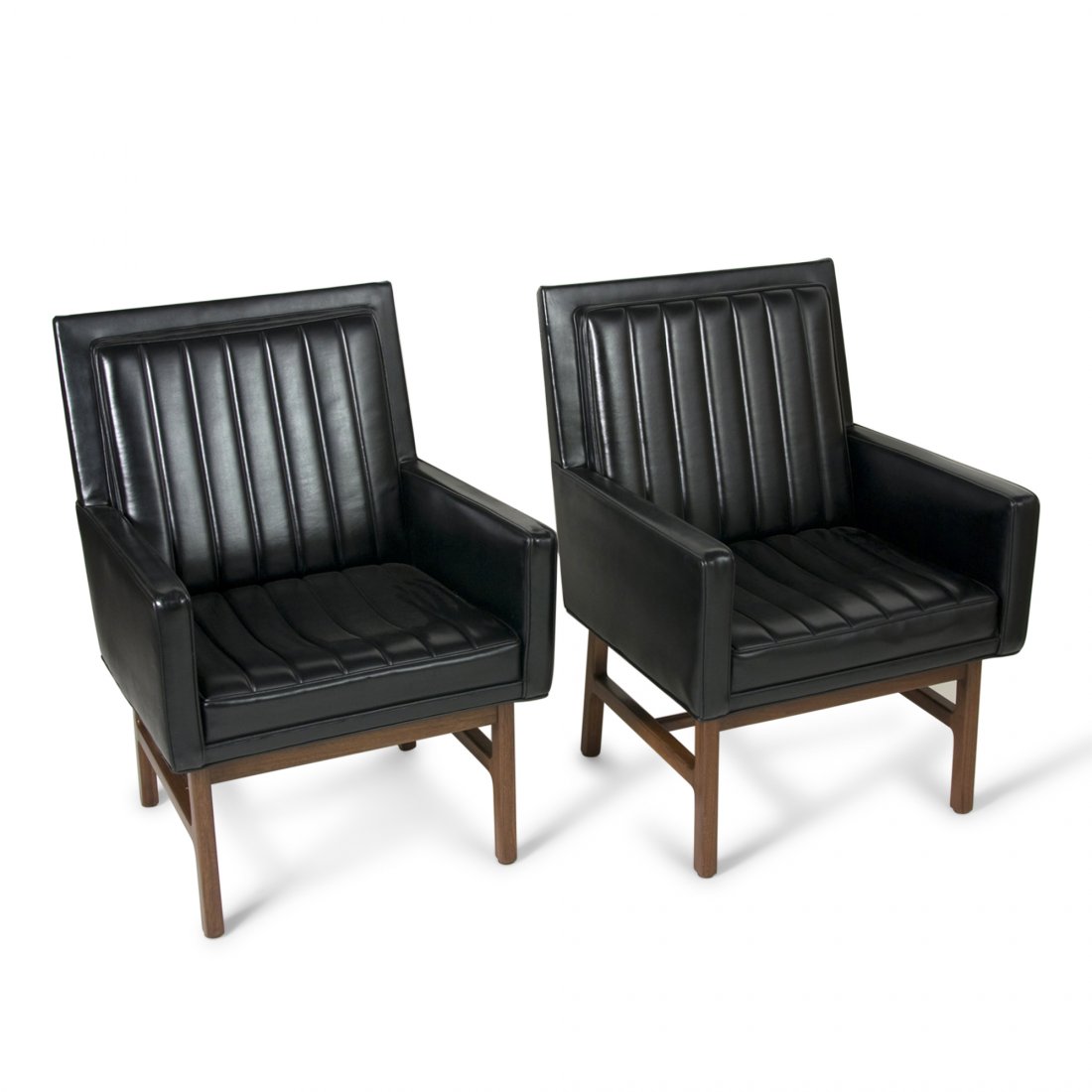 Black Armchairs by Milo Baughman: Pair of black vinyl upholstered lounge chairs, the seats raised on mahogany bases. By Milo Baughman, American early 1960s. Width 25 in, height 35 1/2 in, seat height 17 in, seat depth 18 in.
