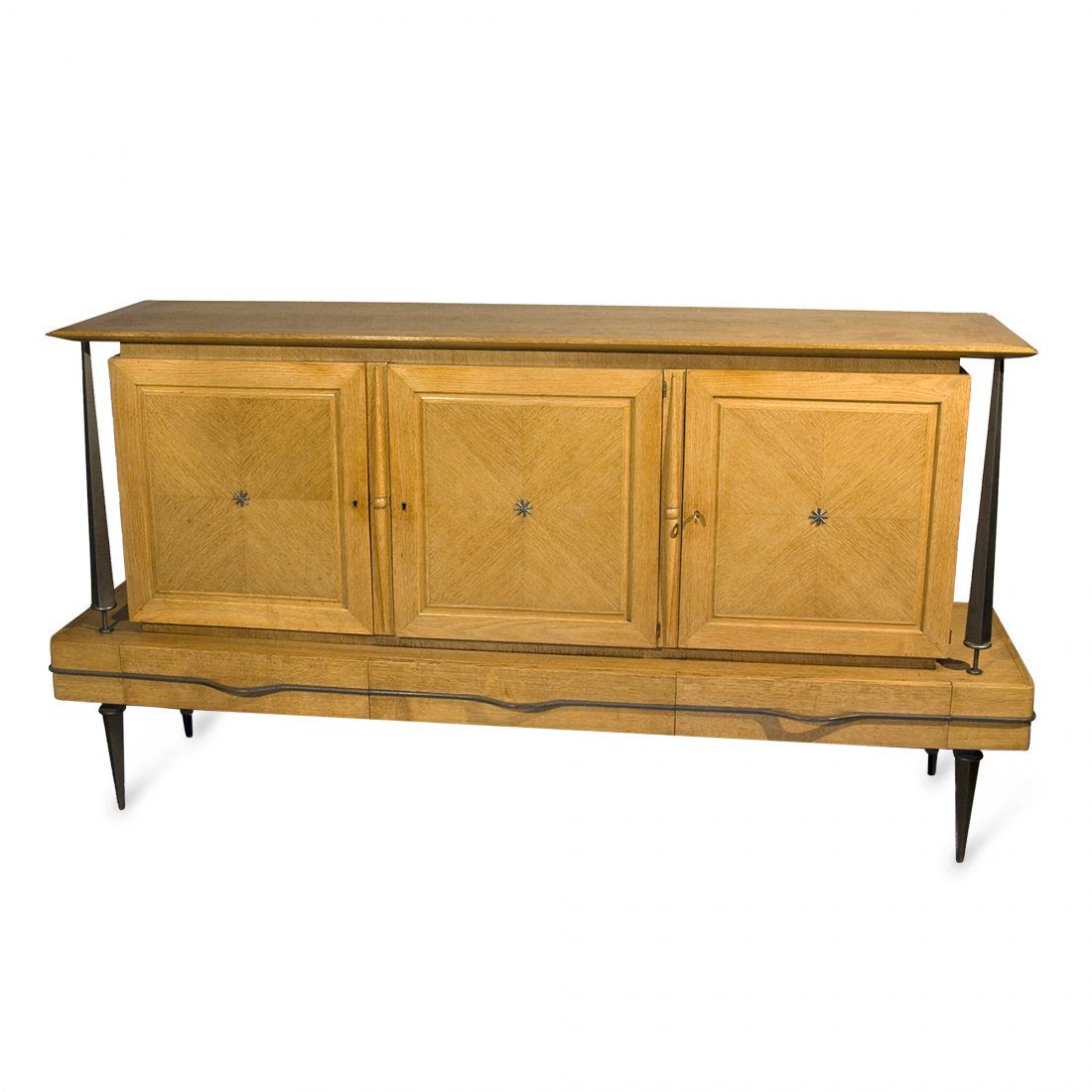 1960s Jules Leleu Attr. Cabinet: Three door oak cabinet with bronze columns and legs, the three doors resting on base, itself having three lower drawers, with bronze star center detail over quarter matched veneer doors, each door con
