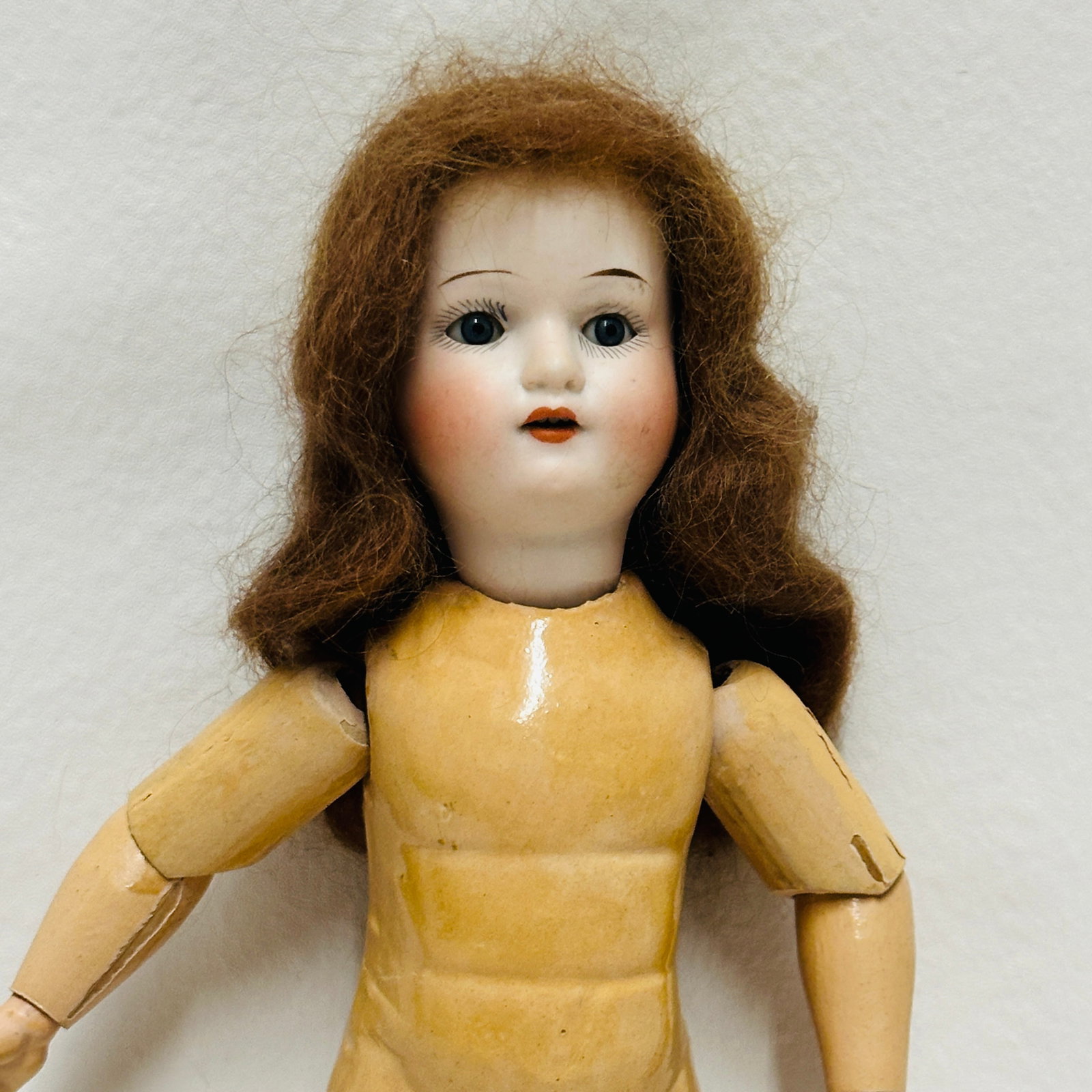 Antique German Armand Marseille 390 Doll: Pale bisque, dark blue sleep eyes, single stroke eyebrows, open mouth with teeth, original auburn mohair wig on compo and wood body with unusual muscular torso and some finish loss. Antique German Arm