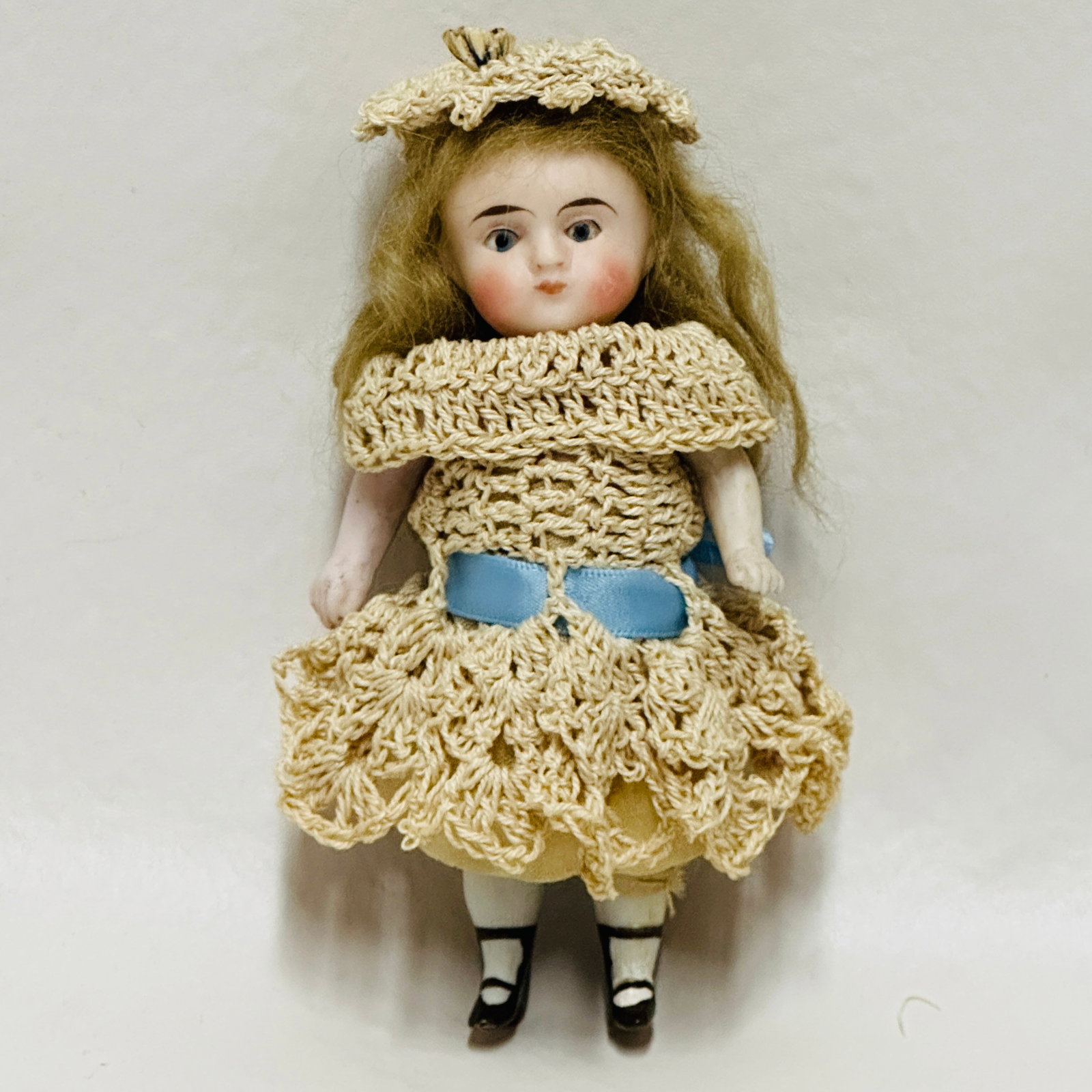 All Bisque Doll in crochet dress: Blue sleep eyes, pursed mouth, heavy brows, painted shoes and socks, original mohair wig, antique crocheted costume with matching hat, All Bisque Doll in crochet dress ------------------ please review