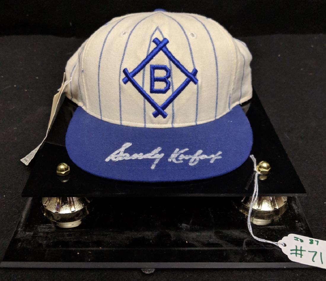 Brooklyn Dodgers Sandy Koufax Autographed Hat: An Authentic Brooklyn Dodgers MLB hat, autographed by Sandy Koufax with a bold silver marker. Kept in quality plastic hat display.