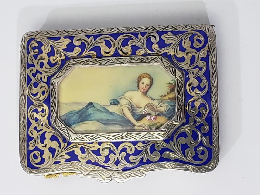 .800 Silver Enamel & Painted Miniature Compact: Appx. 3" x 2 1/8". The center "window" with a painted celluloid (?) miniature of a reclining beauty. Wit blue enamel and foliate scroll work. With gilt interior; mirror in lid of compact. Marked "117 
