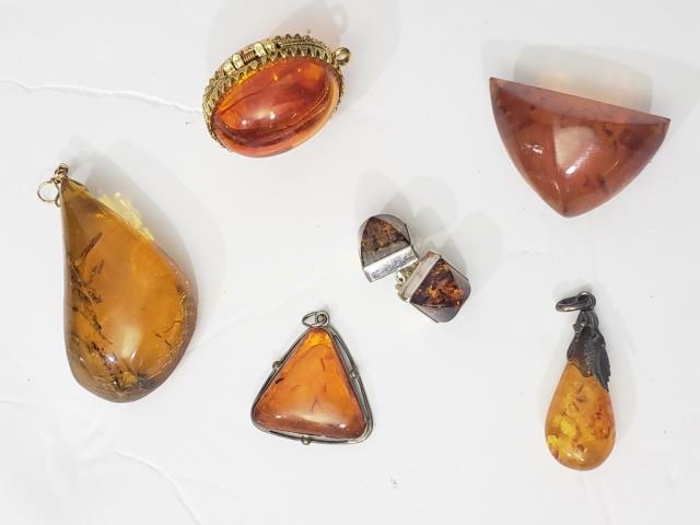 Group of Amber Pins, Earrings, Etc. 6 Pcs: 1) Egg shaped locket, hollow inside, 1.25" tall, 2) rough amber pin, 1.5" largest, 3) rough amber pendant, 2" largest, 4) polished amber earrings, "Lori Bonn" "Sterling, just shy of .5", 5) amber drop