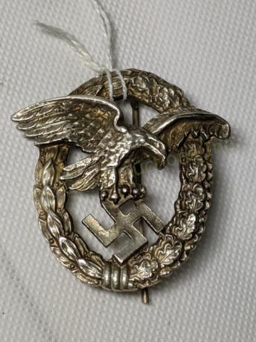 WWII German Third Reich Luftwaffe Pilot Badge: Luftwaffe flying eagle clutching a swastika, surrounded by oak leaf wreath. Stamped "Schwerin Berlin" on the back. 2" X 1 15/16"