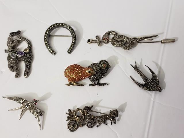 Group of 7 Marcasite & Sterling Pins: 1) flying bird, 1.25", 2) Horse shoe, 3) Car pendant, 4) Two chicks, one with red stones, 5) Snake stick pin with dagger, 6) Flying bird, 7) Horse drawn carriage. Total weight -1.35 Oz. Troy.