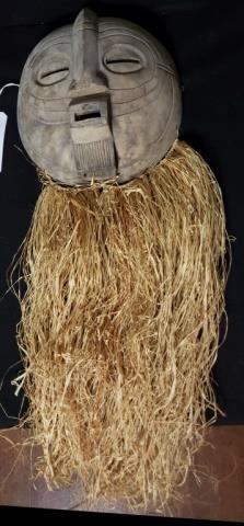 Large Hand Carved African Bearded Mask: Hand carved and finished smooth on the face. With hand tied straw beard. Approximately 45" from head to beard, the mask itself is 4 1/2" X 12 1/2" diameter.