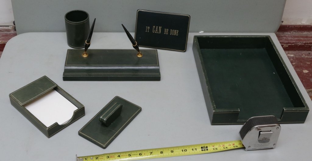 An Asprey London 6 pc. Green Leather Desk Set: An Asprey London green leather desk set. Ink blotter, framed "It Can Be Done" motto, double pen stand, note pad holder, "in" box, and a pen holder cup.