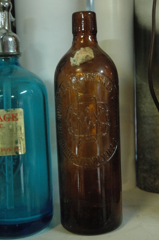 Vintage bottle collection, including blue seltzer: One Blue New Jersey seltzer bottle, The Bear Bronx NY bottle, and a clear Duffy Malt Whiskey Co. brown bottle.
