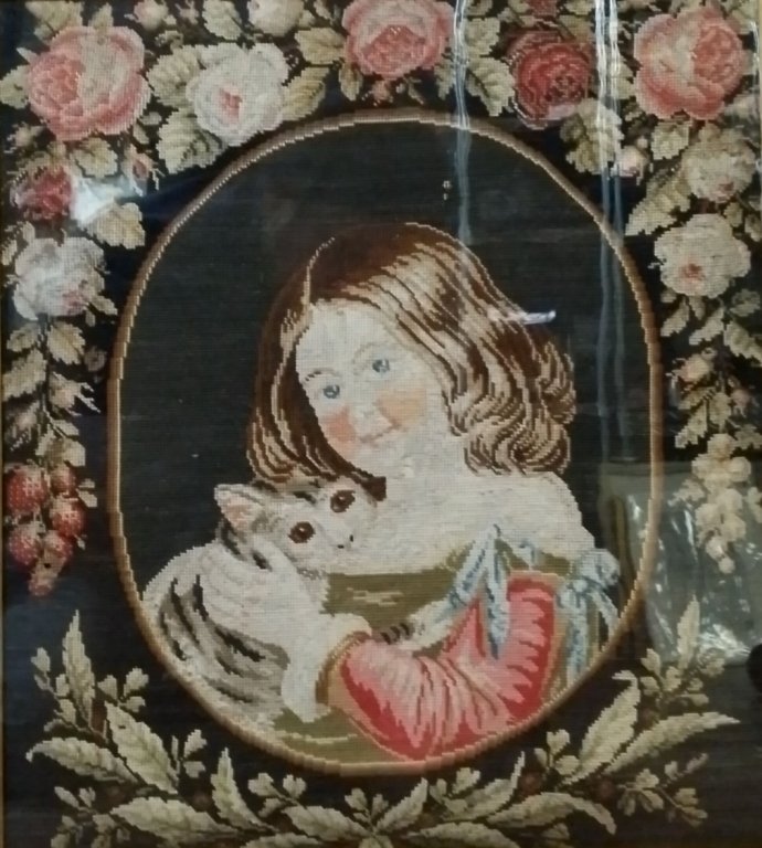 A Victorian needlepoint of a young girl with a cat: The antique needlepoint in a birds eye maple frame. Sight size 16.5" x 14.5".