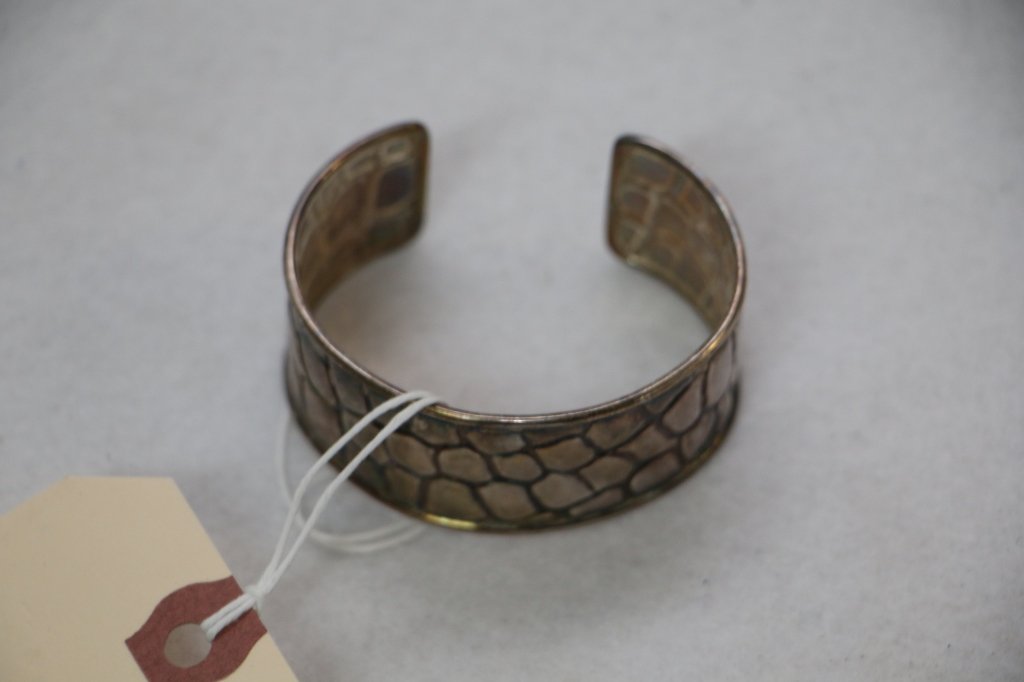 A Sterling Silver Tiffany & Co Bracelet: A Sterling silver Tiffany & Co. cuff Bracelet with a alligator skin pattern. Marked "Tiffany & Co./ Italy/ (star) 540 FI .925". C. late 1970's or 1980's.