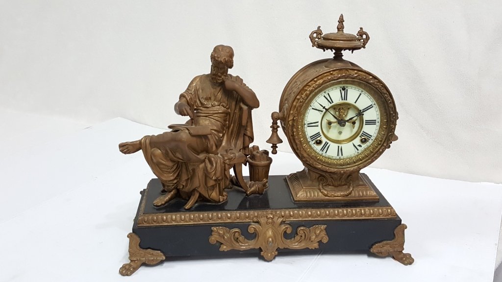 Ansonia Arion Figural Mantle Clock: NEW YORK, CIRCA 1890s-1910s A white metal Ansonia Arion figural mantle clock. The clock has a porcelain face with an open escapement. The clock depicts a Renaissance man with chalice and book in hand.