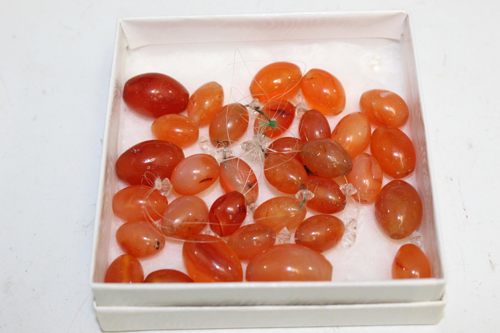 A box of carnelian beads.: A box of carnelian beads. Largest L 2.5 cm.