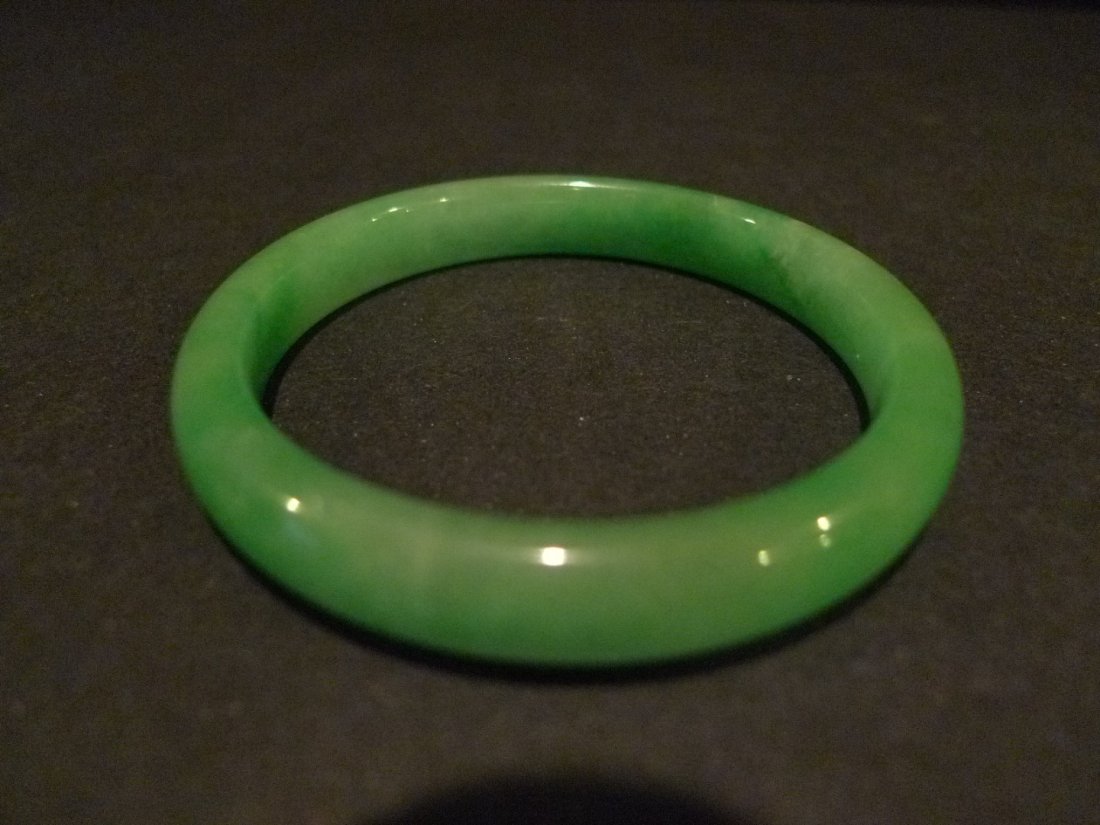 CHINESE APPLE GREEN JADEITE BANGLE: CHINESE CARVED JADEITE BANGLE. NATURAL JADEITE. INSIDE DIAMETER 5.8CM. OUTSIDE DIAMETER 7 CM. 14 MM WIDE. 58 GRAMS. PROVENANCE - BETHESDA MD ESTATE