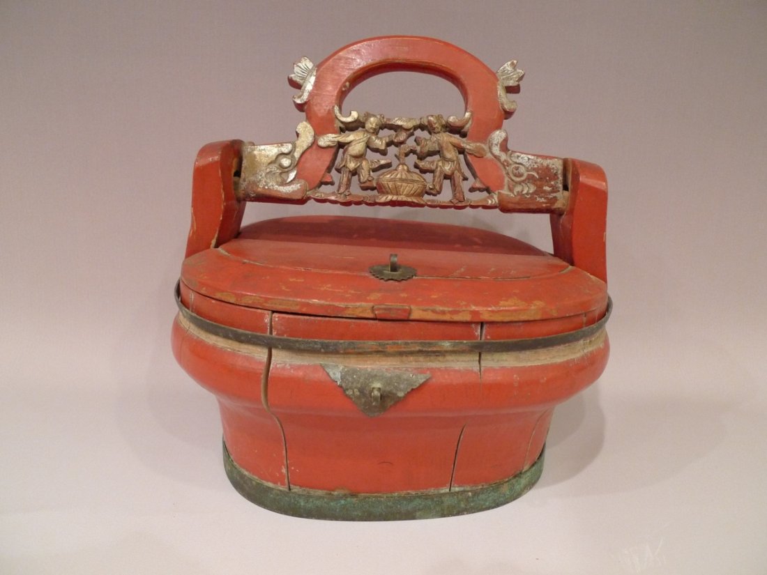 CHINESE REPUBLIC PERIOD RED LACQUER WOOD WEDDING BASKET: Red lacquer on carved wood wedding basket. Gilt paint on figures of children at play. Brass ring around the body and around the base. Circa 1910s. L 11” x W 9” x H 12” Provenance: From a Chevy C