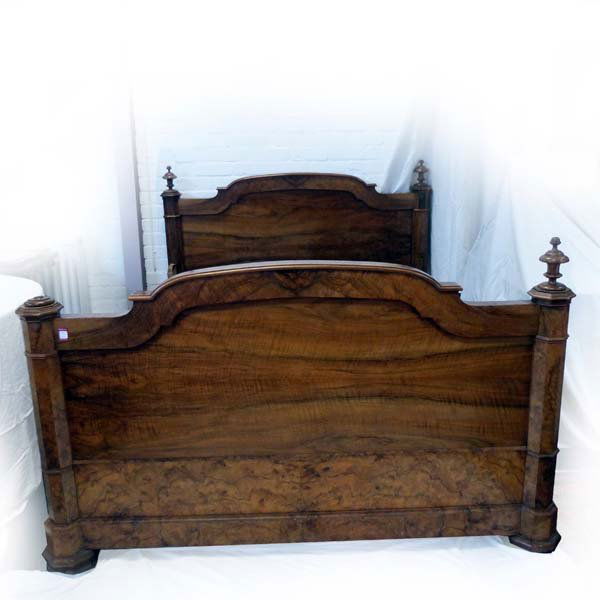A large Victorian walnut bed and base, having four octa: A large Victorian walnut bed and base, having four octagonal corner posts topped with turned finials, with panelled head and tailboards. (58in x 76in inner)