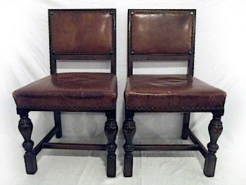 A set of four leather upholstered oak dining chairs by : A set of four leather upholstered oak dining chairs by John Taylor & Sons of Edinburgh, the padded brass studded backs above stuffover upholstered seats, raised on baluster turned legs joined by recta