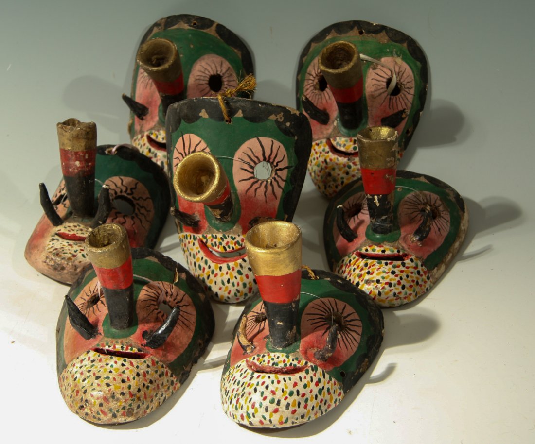7 Small Trumpet-Nosed Masks: This lot consists of 7 masks from Mexico from the mid-20th century. These masks are made from wood and have playful faces with long cone noses. Currently, sting has been laced through the eye-holes to