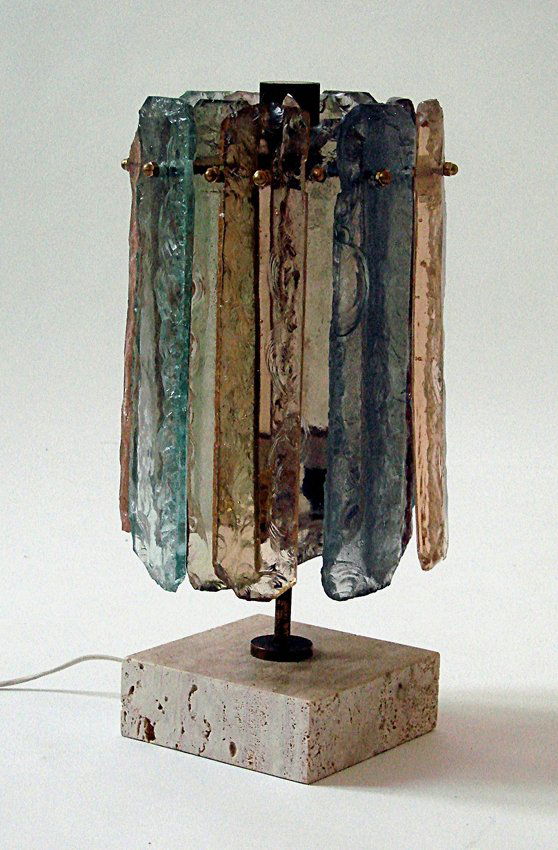 Table lamp Manifattura Italiana, 1950 ca.: Table lamp in cheseled thick glass. Brass structure, travertine base. Dimensions: h 42 cm, diameter 20 cm. Lampada da tavolo in vetro scolpito di grosso spessore. Struttura in ottone, base in traverti
