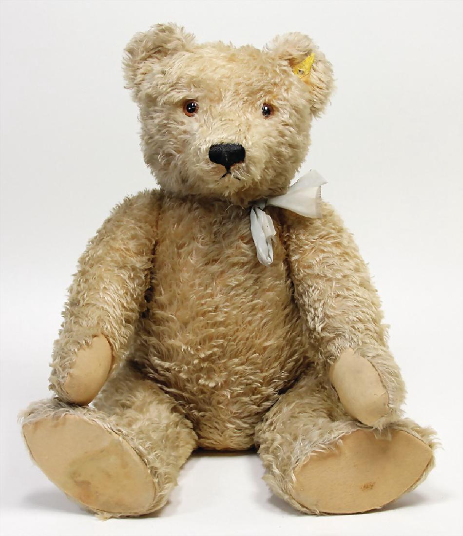 Steiff Originalteddy, Nachkrieg, 70 cm, Schild, Knopf: Steiff Originalteddy, Nachkrieg, 70 cm, Schild, Knopf und gelber Fahne, leichter Buckel, abgeknickte Arme, Pappsohlen unter den Füßen, etwas ausgeblichen, schönes volles Mohair, au&szl