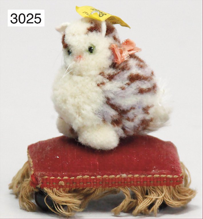 STEIFF, wool miniatures, Nomotta-wool, cat sitting, wit: STEIFF, wool miniatures, Nomotta-wool, cat sitting, with button and yellow cloth tag label, No. 3505.40, cloth tag label in good condition, jointed head, glass eyes, whiskers, ribbon at the side, moha