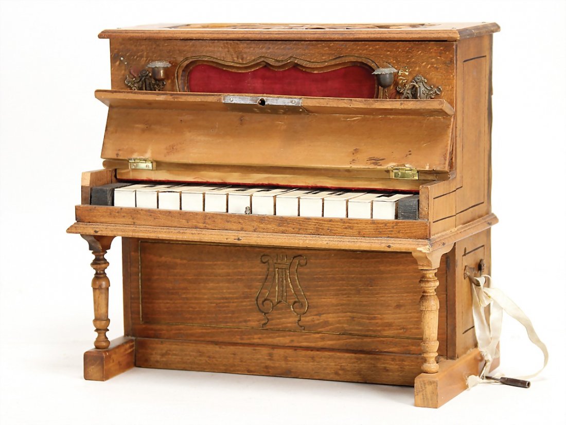 doll's piano, around 1900, height 29 cm,some places of: doll's piano, around 1900, height 29 cm,some places of the wood were supplemented, in front 2 candelabrums made of brass/sheet metal, playable, additionally with music mechanism German Description Pup