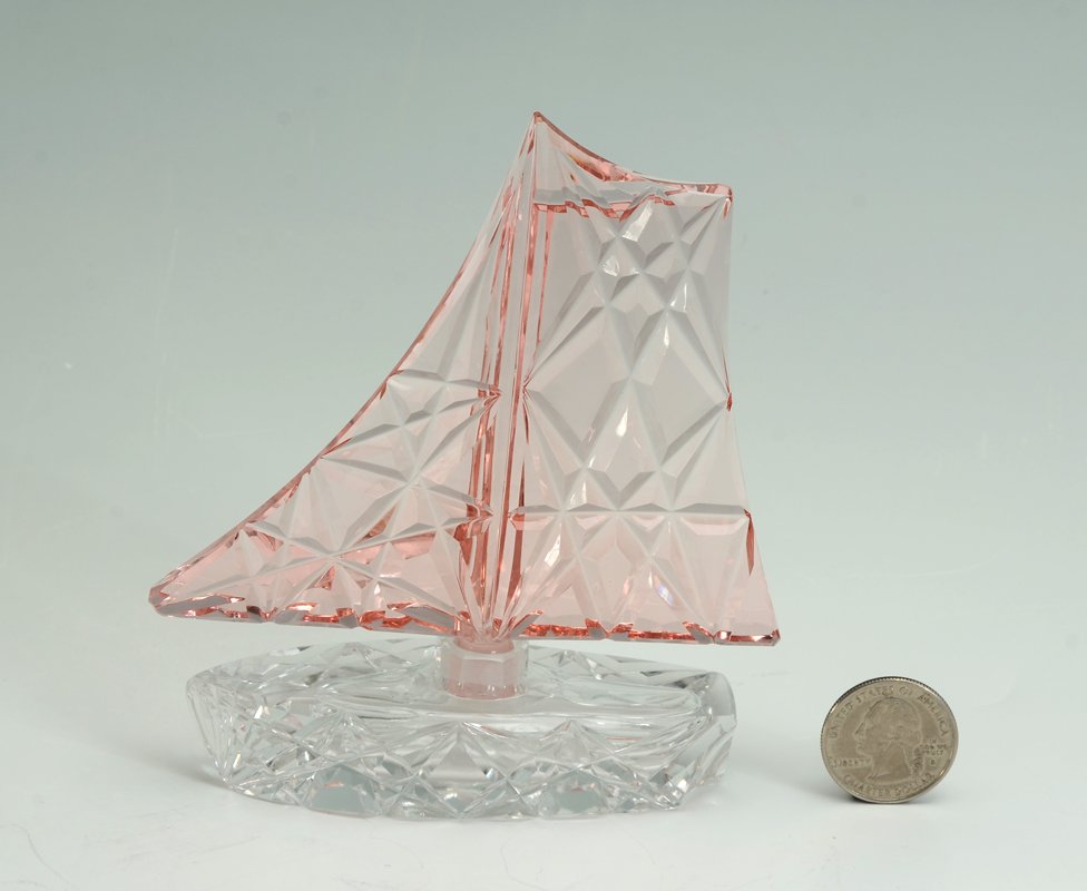 CRYSTAL FIGURAL SAILBOAT PERFUME BOTTLE: CRYSTAL FIGURAL SAILBOAT PERFUME BOTTLE: Clear cut crystal boat form base with pink cut crystal sail stopper/dabber. No makers mark of label. Overall with stopper 4 7/8" h. x 4 1/4".