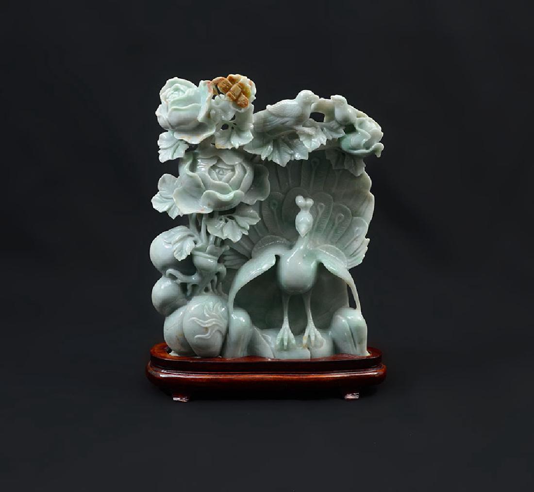 CHINESE CARVED JADEITE PEACOCK AND FRUIT GROUP: CHINESE CARVED JADEITE PEACOCK AND FRUIT GROUP: Apple green and brown jadeite or similar stone figure of a peacock, gourd vines, flowers, butterfly and other birds. Affixed to wood stand, overall with