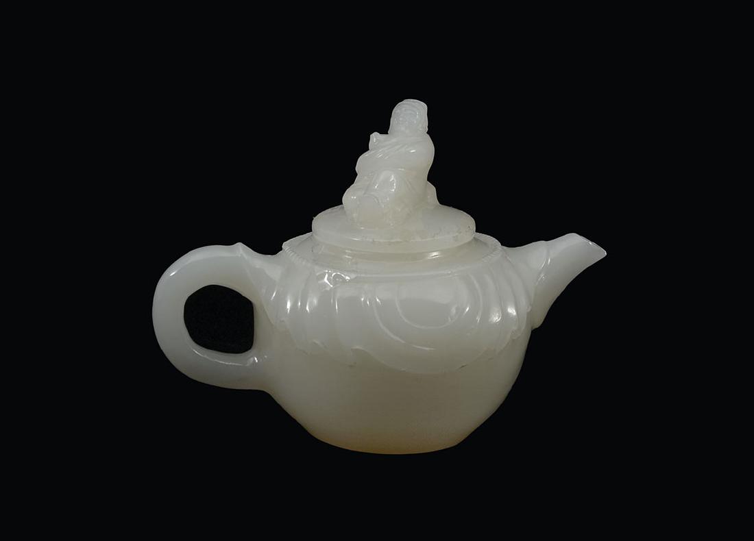 CHINESE CARVED WHITE AGATE TEAPOT: CHINESE CARVED WHITE AGATE TEAPOT: Creamy white agate or similar stone, lid with carved reclining man finial, body with swags. Overall 4 1/8'' h. x 5 3/8''.