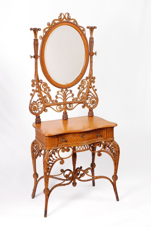 ANTIQUE NATURAL CURLICUE WICKER VANITY: ANTIQUE NATURAL CURLICUE WICKER VANITY: Rare vanity with central oval beveled glass mirror, framed and supported by curlicue wicker. Shaped tiger oak top over single drawer, wicker legs and stretchers