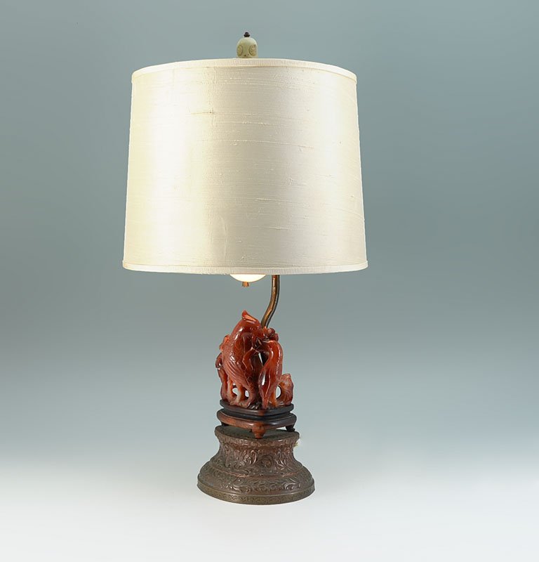 CHINESE CARVED CARNELIAN AGATE BIRD LAMP: CHINESE CARVED CARNELIAN AGATE BIRD LAMP: Figural group of 2 birds on branches carved from carnelian agate or similar stone on carved wood base, all on embossed metal base. Single socket fixture, fini