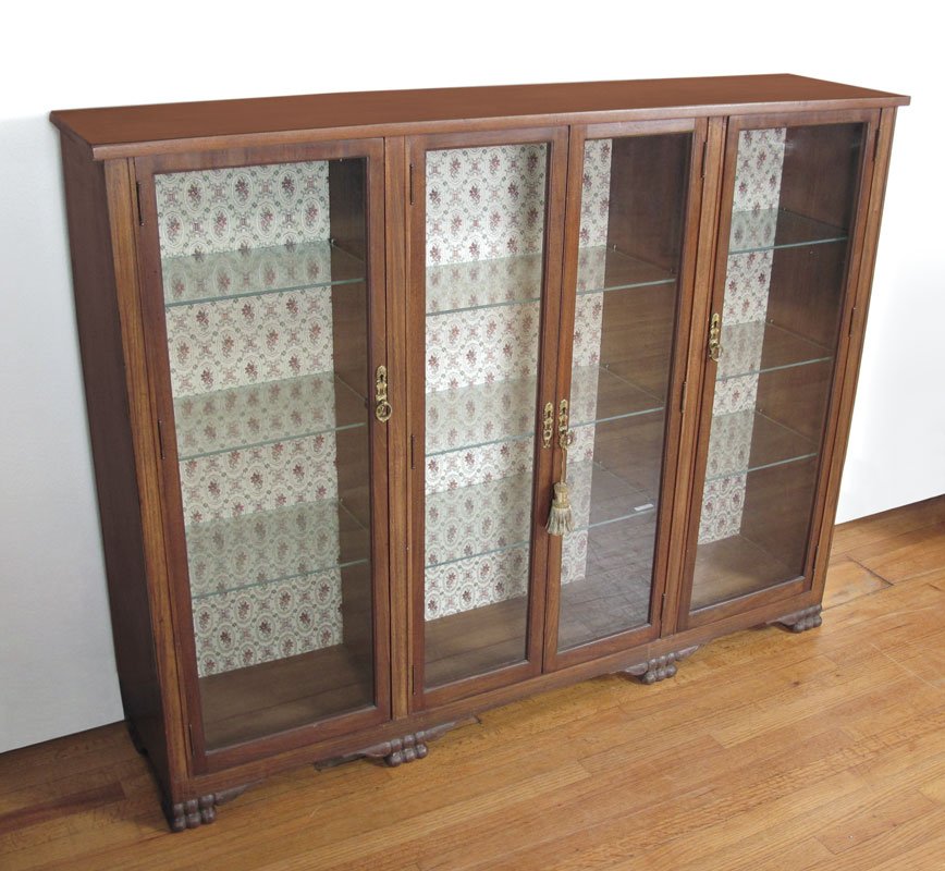 FOUR DOOR BOOKCASE CABINET: FOUR DOOR BOOKCASE CABINET: Four glass doors, interior with glass shelves and fabric covered back, paw feet across the front. 49 1/2" x 63 1/2" x 14".