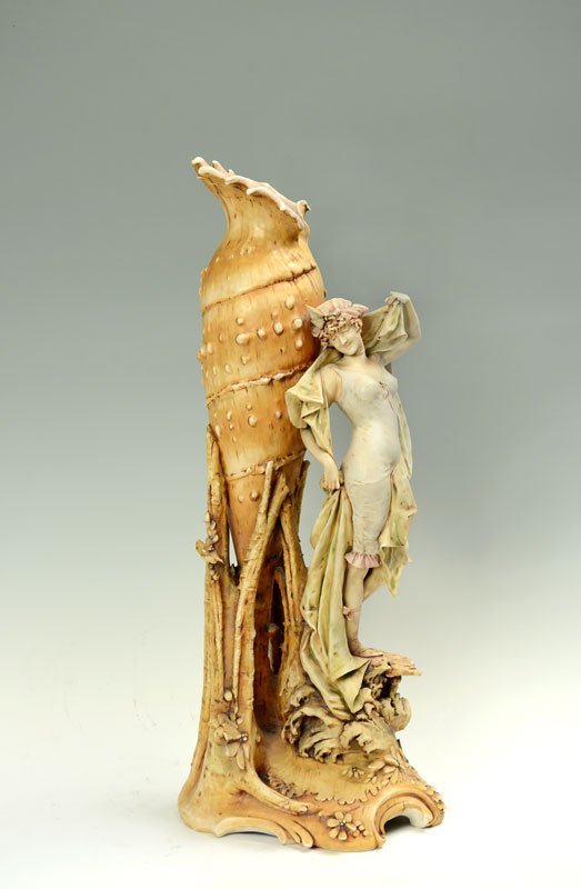 RIESSNER & STELLMACHER TURN TEPLITZ FIGURAL VASE: RIESSNER & STELLMACHER AMPHORA TURN TEPLITZ FIGURAL VASE: Stylized shell vase with figure of maiden holding draped sheets, applied floral decoration. Riessner & Stellmacher mark on base. 26" h. x 8 1/