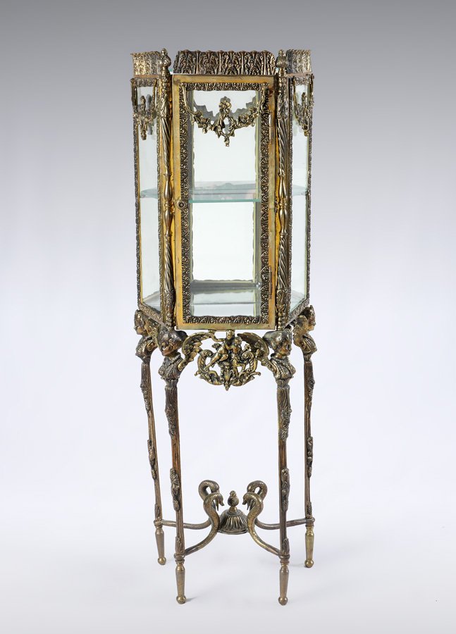 DIMINUTIVE ROCOCO STYLE DISPLAY CABINET: DIMINUTIVE ROCOCO STYLE DISPLAY CABINET: Cast brass frame, glass top, tapered sides and door. Skirt with neo-classic putti motif decoration. 4 winged maiden busts above legs, figural snake stretchers,