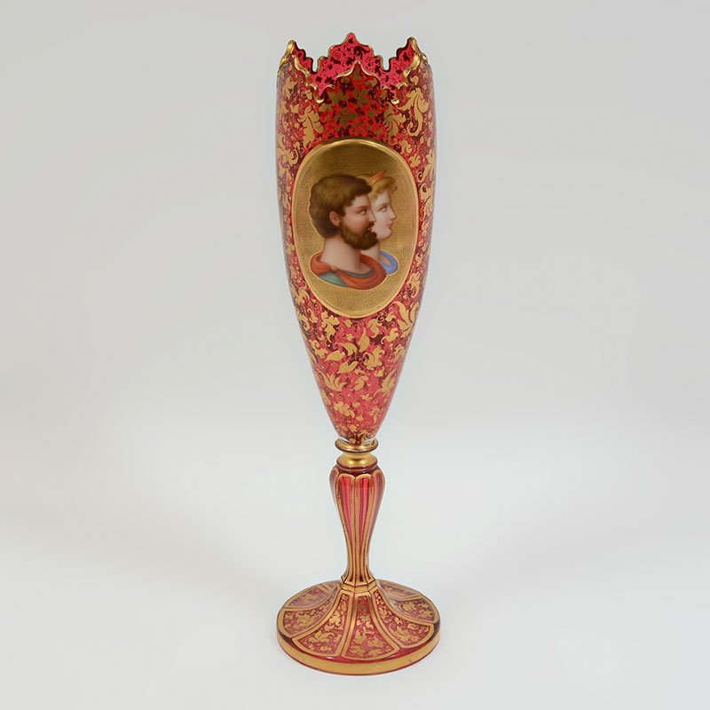 BOHEMIAN CRANBERRY GLASS PORTRAIT VASE: BOHEMIAN CRANBERRY GLASS PORTRAIT VASE: Scalloped rim, cranberry glass body with applied portrait of noble man and woman, balance of body with gilt arabesque foliate decoration, 16" h. x 4 1/2".