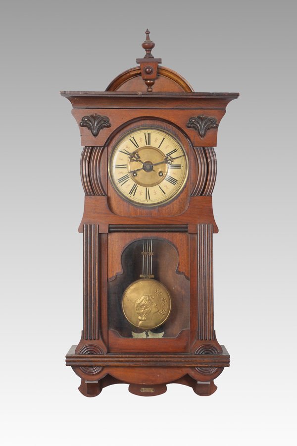 JUNGHANS GERMAN WALL CLOCK: JUNGHANS GERMAN WALL CLOCK: Walnut case with arched pediment, spire finial, Round bezel, lower shaped glass window, retailer E. Holzmann brass tag on foot. Dial with paper chapter ring, Roman numerals