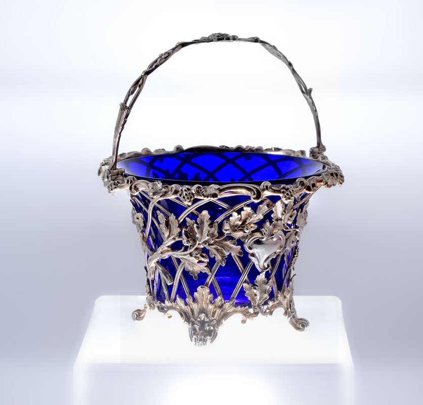 1867 ENGLISH SILVER COBALT LINED ACORN BASKET: 1867 ENGLISH SILVER COBALT LINED ACORN BASKET: Reticulated basket with oak leaves and acorn design, unknown maker E, J, B, & W, 1867 London hallmarks, articulated handle, 4 1/2" h. x 6". Cobalt blue i