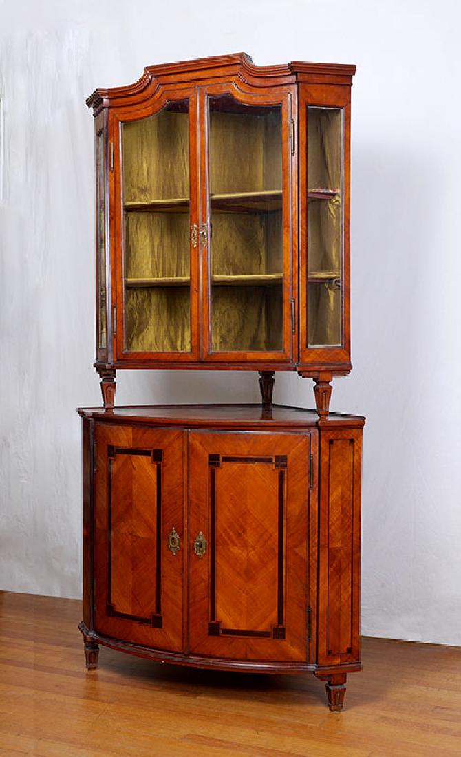 19TH CENTURY BIEDERMEIER CORNER CABINET: 19TH CENTURY BIEDERMEIER CORNER CABINET: Top with glass doors, canted glass corners, cloth lined interior with 2 shelves. Barrel front base with 2 parquetry inlaid doors, single interior shelf, overal