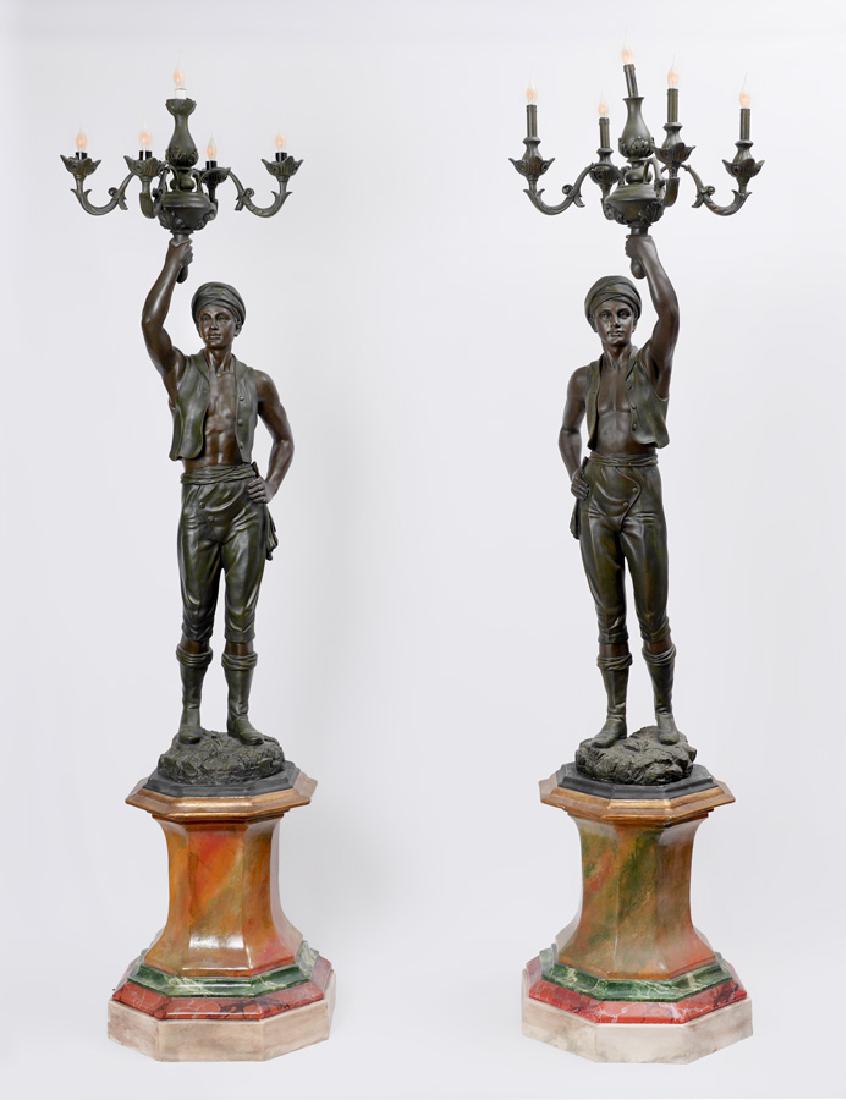 PAIR BLACKAMOOR TORCHIERE FLOOR LAMPS: PAIR BLACKAMOOR TORCHIERE FLOOR LAMPS: 20th Century composite construction molded figural blackamoor men holding 5 light fixture, approx. 63'' h. x 23'' dia.. Sold with molded composite octagonal poly