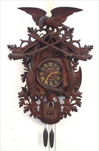 LARGE BLACK FOREST GERMAN CUCKOO CLOCK: LARGE BLACK FOREST GERMAN CUCKOO CLOCK: Finely carved in a gaming motif, faux ivory Roman numerals and hands, pine cone weights. 37''h. x 25 1/2'', allow 13'' space away from wall.