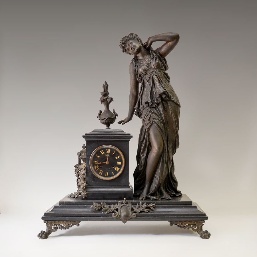 FRENCH TALL FIGURAL WOMAN MANTLE CLOCK: FRENCH TALL FIGURAL WOMAN MANTLE CLOCK: Patinated cast spelter figure of a neo-classical style standing woman with flowing dress, slate clock case with urn finial, floral side decoration, carved slate