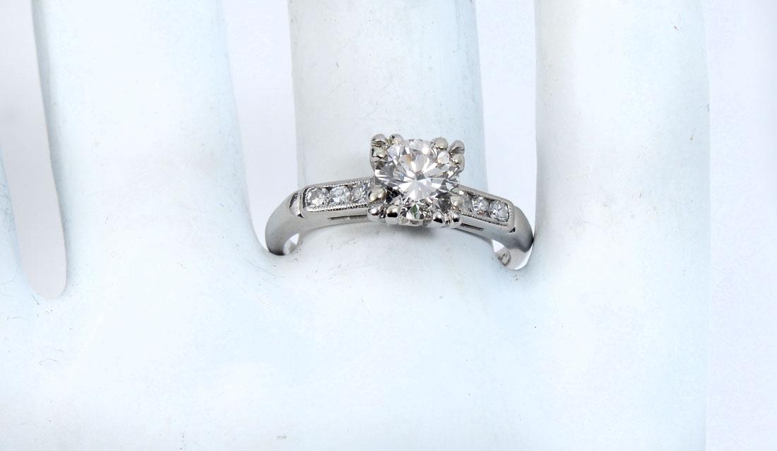 PLATINUM RETRO DECO 1.10 CT DIAMOND RING: PLATINUM RETRO DECO 1.10 CT DIAMOND RING: Classic fishtail setting features 1.10 CT circular brilliant cut diamond with SI1 clarity and H color. Complimented by 6 round single cut diamonds approx .15 