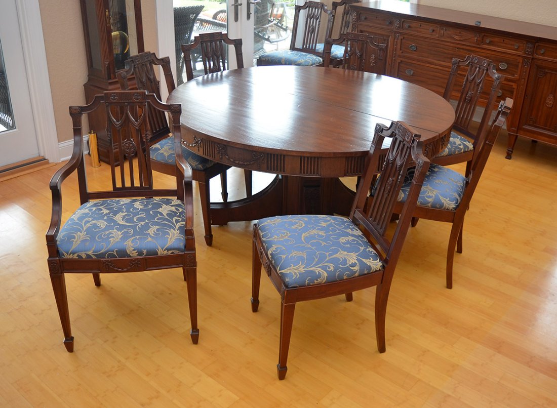 CARVED ROUND MAHOGANY DINING TABLE AND 10 CHAIRS: CARVED ROUND MAHOGANY DINING TABLE AND 10 CHAIRS: Table with round top, fluted skirt with carved floral swags, base on 4 shaped legs and castors measures 30" h. x 60" dia., the 5 leaves measures 11".