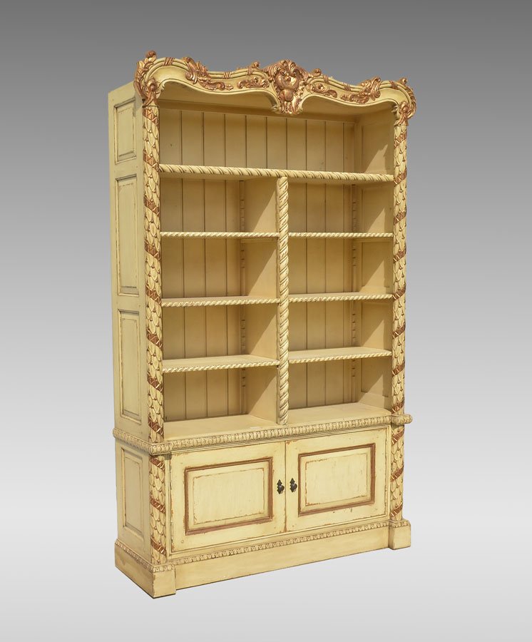 CONTINENTAL CARVED & PAINTED BOOKCASE: CONTINENTAL CARVED & PAINTED BOOKCASE: Rococo style with carved foliate crest, style with carved scales on columns, open shelves with twist carved fronts, 2 lower doors. Yellow and gilt decorated, 91 