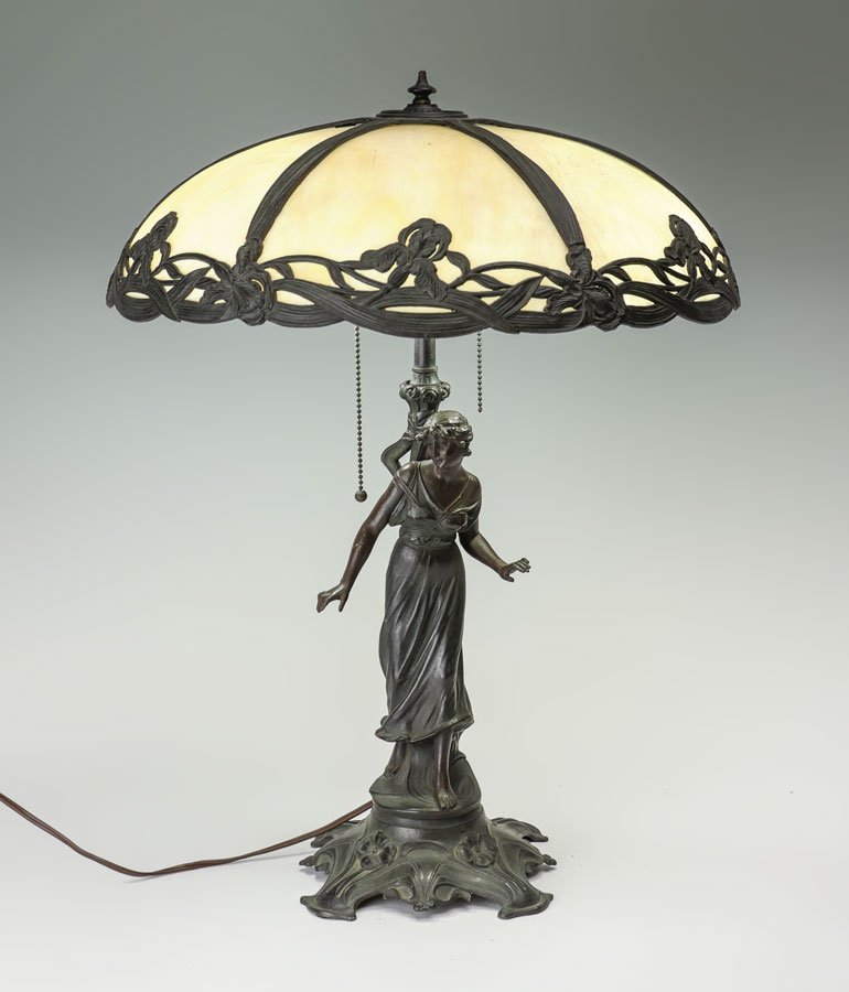 FIGURAL SLAG GLASS TABLE LAMP: FIGURAL SLAG GLASS TABLE LAMP: Patinated spelter figure of a standing woman on art nouveau style base, double socket fixture, no visible makers mark, 23 3/4" h. x 7 1/2". Art nouveau floral filigree f