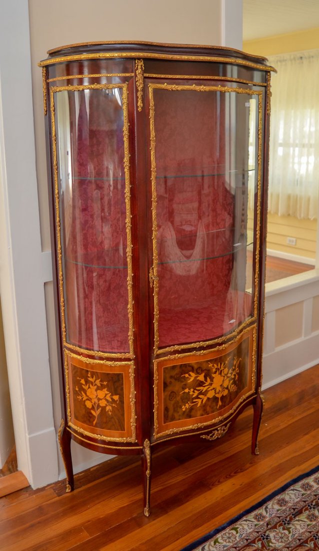 TRIPLE BOW CURIO CABINET: TRIPLE BOW CURIO CABINET: 3 inset curved glass panels with gold toned scrolling foliate metal work and ormolu. 3 glass shelves in front of a crimson red silk lining with a foliate design. Wood-burned 
