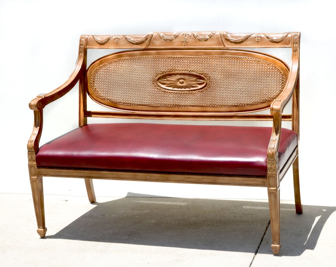 CARVED FRENCH LEATHER SETTEE: CARVED FRENCH LEATHER SETTEE: Upholstered in a brick red leather with a carved oval back with cane work and a carved flower center medallion. Carved draped floral design. Approx. 35.75" h x 47.5" l x 