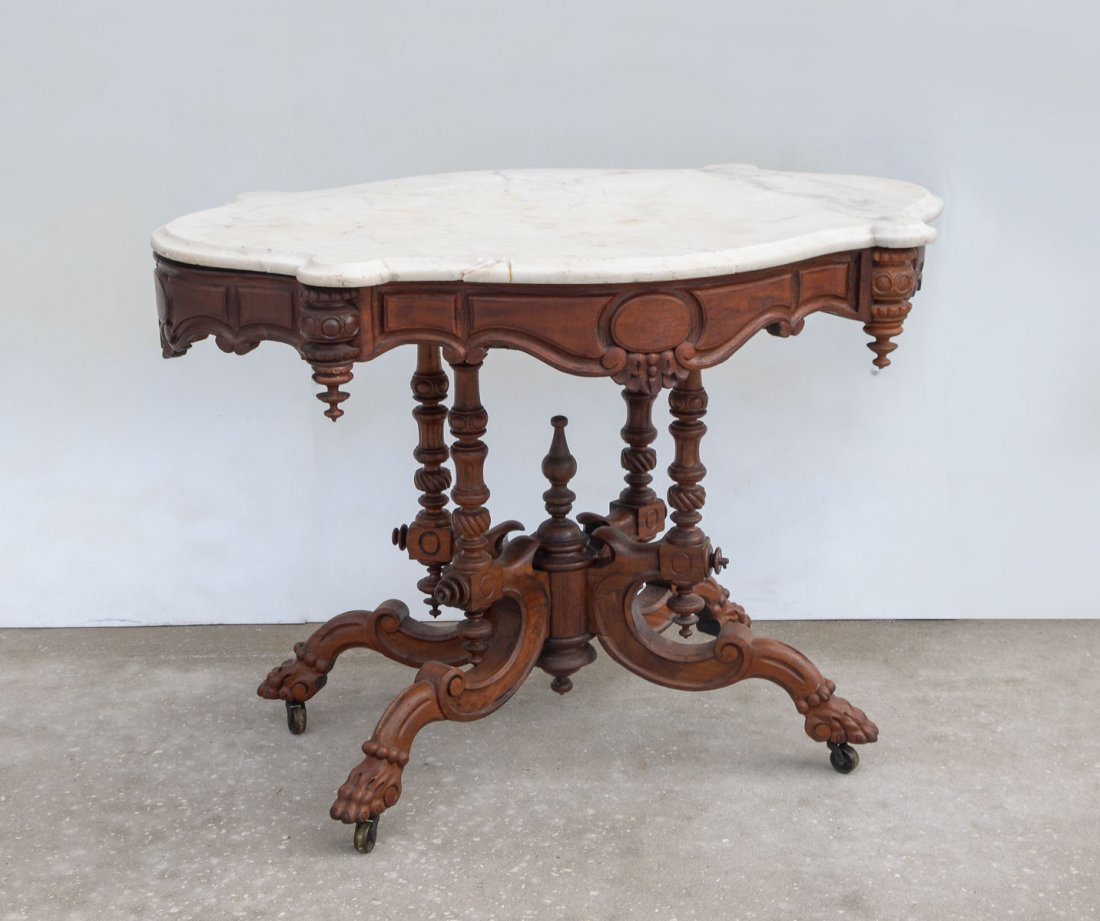 VICTORIAN TURTLE TOP MARBLE TABLE: VICTORIAN TURTLE TOP MARBLE TABLE: White marble turtle top Victorian gothic style table. Heavily turned & carved framework, with carved scrolling supports with paw feet on casters. Approx. 28" h x 39.