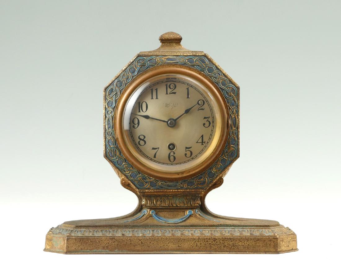 TIFFANY STUDIOS GILT BRONZE MANTLE CLOCK: TIFFANY STUDIOS GILT BRONZE MANTLE CLOCK: Gilt bronze textured mantle clock with a blue & gold geometrical pattern encompassing the face. Scrolling foliate border on base with underside impressed Tiff