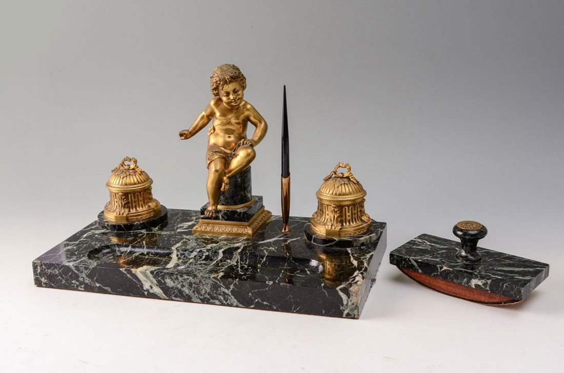 GILT BRONZE & MARBLE FIGURAL PUTTI DESK SET: GILT BRONZE & MARBLE FIGURAL PUTTI DESK SET: Green variegated marble base, center figural gilt bronze seated putti, inkwell either side, no inserts, measures 10 1/2 h. x 17" x 9". Sold with marble and